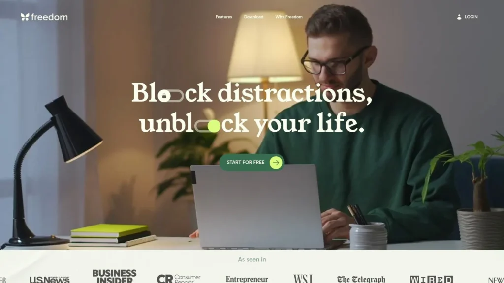 Freedom app homepage with the headline “Block distractions, unblock your life,” showing a man working on a laptop at a desk with a start for free button and media logos featured below.