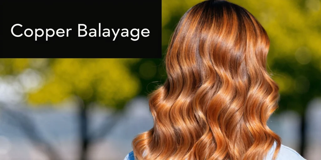 Wavy shoulder-length hair with copper balayage highlights against a blurred outdoor background.