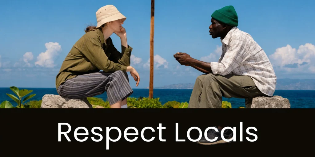Two travelers talking by the ocean beside “Respect Locals” text under a bright blue sky.