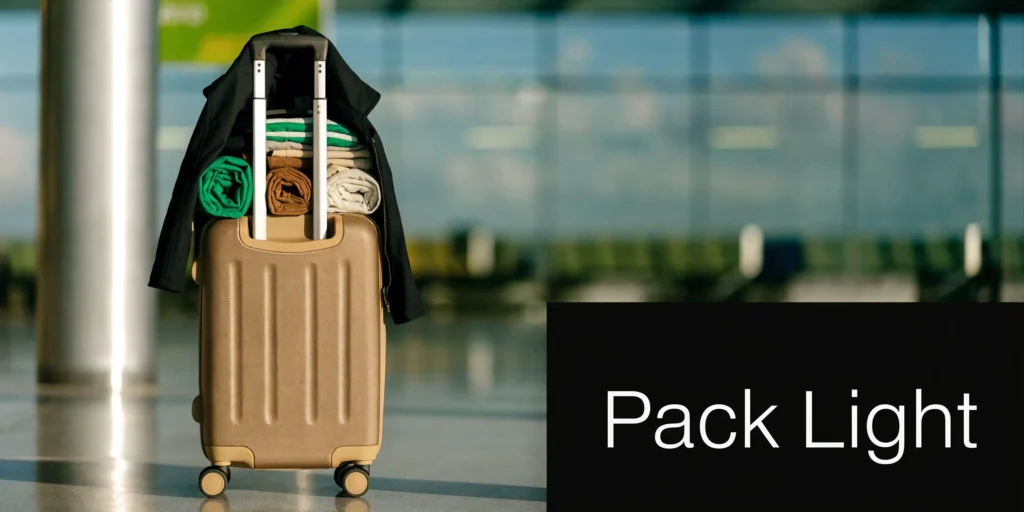 Packed suitcase with folded clothes and jacket beside “Pack Light” text in an airport terminal.